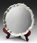 A modern silver salver, of plain circular form with scalloped edge border and raised upon four hoof feet