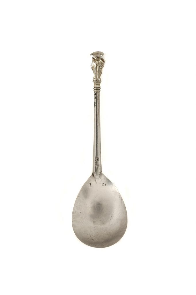 Apostle spoon depicting St. John with deep fig-shaped bowl inscribed on the back with the initials IG, and a thick, tapering stem ending with a moulded capital, on which the figure stands
