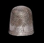 A bell-shaped silver thimble with domed upper face